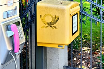 Ein Briefkasten steht neben einer Telefonsäule (Symbolbild): Das Porto wird im Januar teurer.