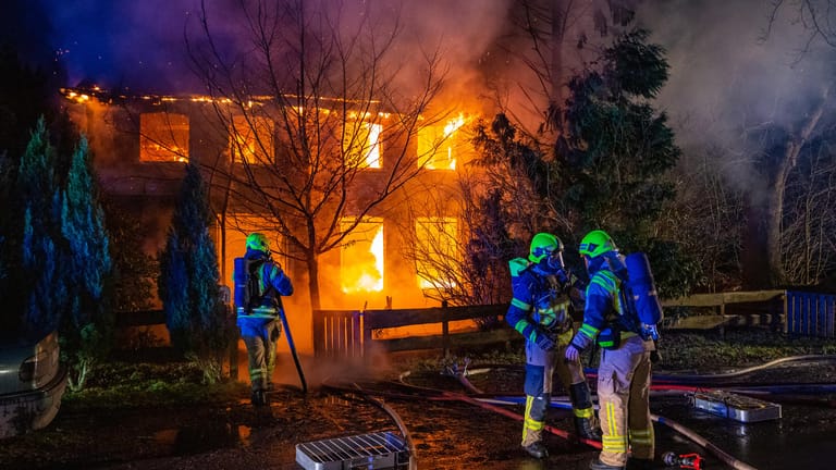 Feuerwehrleute stehen vor dem brennenden Haus: Das Gebäude war einsturzgefährdet, weshalb die Einsatzkräfte nur von außen löschen konnten.