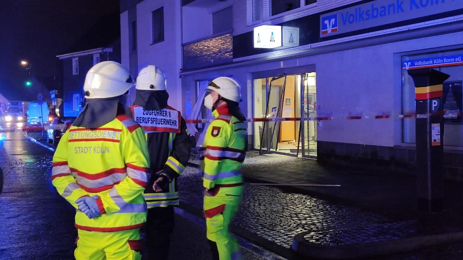 Feuerwehrleute stehen vor der zerstörten Bankfiliale in Köln-Brück: Drei Unbekannte sollen an der Sprengung beteiligt gewesen sein.