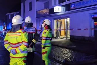 Feuerwehrleute stehen vor der zerstörten Bankfiliale in Köln-Brück: Drei Unbekannte sollen an der Sprengung beteiligt gewesen sein.