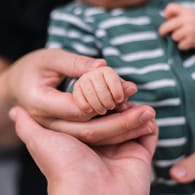 Eltern halten die Hand eines Babys (Symbolbild): Eine Person muss über weibliche Fortpflanzungsorgane verfügen.