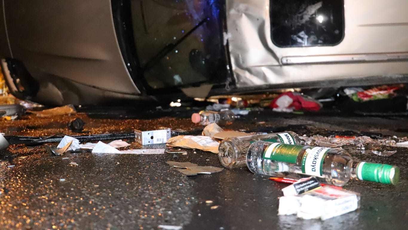 Eine Nahaufnahme der Unfallstelle: Auf dem Boden um das Fahrzeug sind eindeutig Wodkaflaschen der Marke "Moskowskaya" zu erkennen.