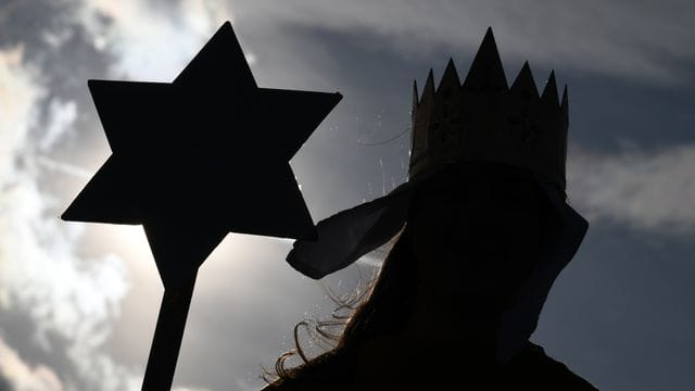Ein Sternsinger hält einen Sternstab in der Hand