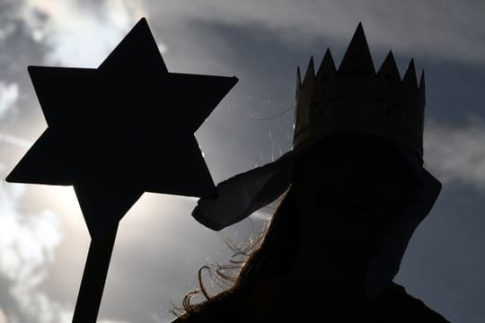 Ein Sternsinger hält einen Sternstab in der Hand