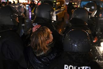 Polizisten in Schutzausrüstung tragen während der nicht genehmigten Demonstration von Gegnern der Corona-Politik eine Teilnehmerin weg: Rund 5.000 Menschen versammelten sich am Mittwochabend in der Münchner Innenstadt.