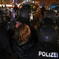 Polizisten in Schutzausrüstung tragen während der nicht genehmigten Demonstration von Gegnern der Corona-Politik eine Teilnehmerin weg: Rund 5.000 Menschen versammelten sich am Mittwochabend in der Münchner Innenstadt.