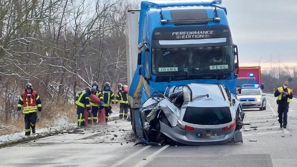 Feuerwehrleute stehen neben den Unfallfahrzeugen: Die Front des Pkws ist komplett eingedrückt. Feuerwehrleute stehen neben den Unfallfahrzeugen: Die Front des Pkws ist komplett eingedrückt.