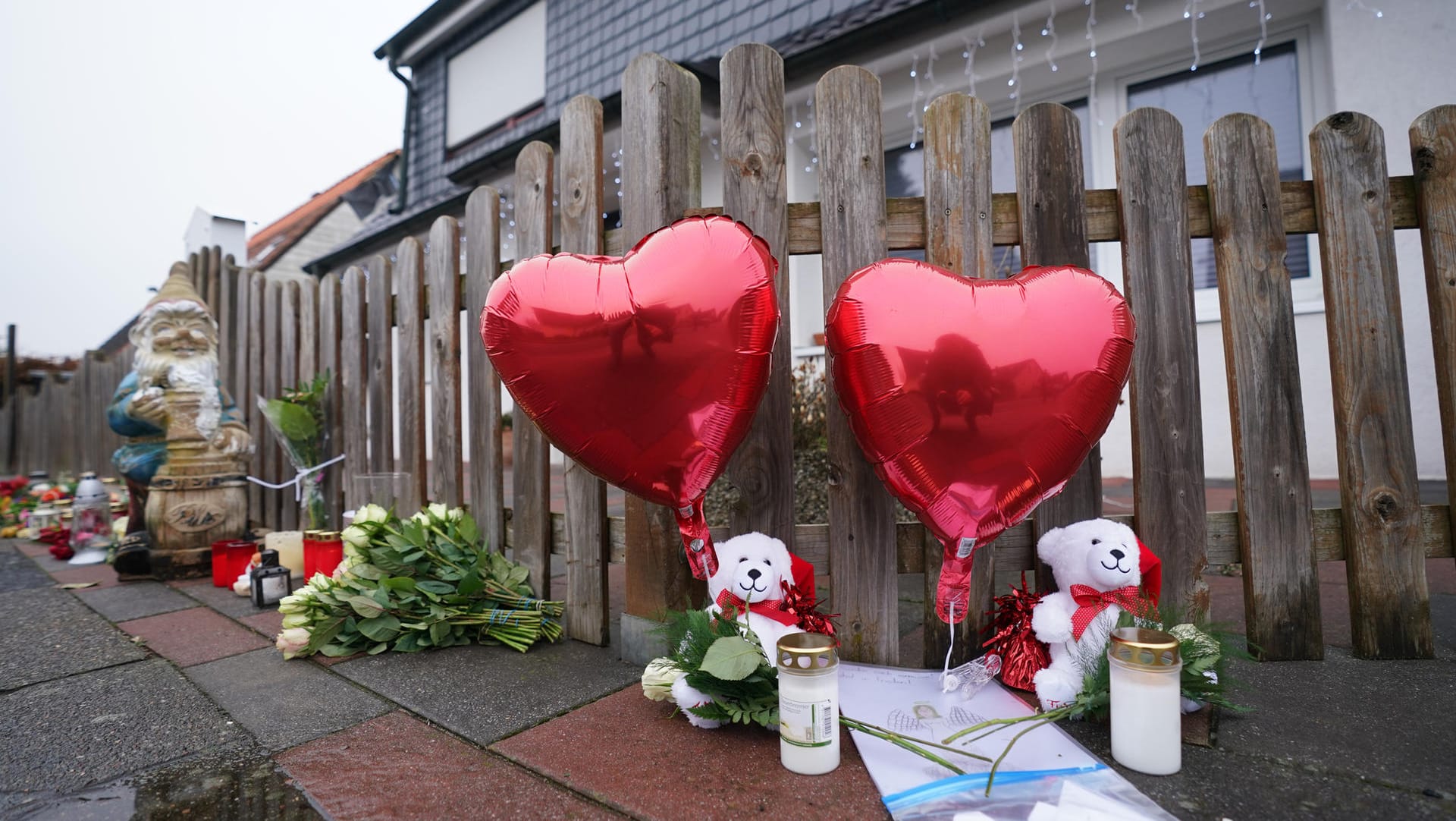Luftballons in Herzform, Plüschtiere, Kerzen und Blumen stehen vor dem Eingang zu einem Haus (Archivbild): Die Mutter hat als Einzige überlebt.
