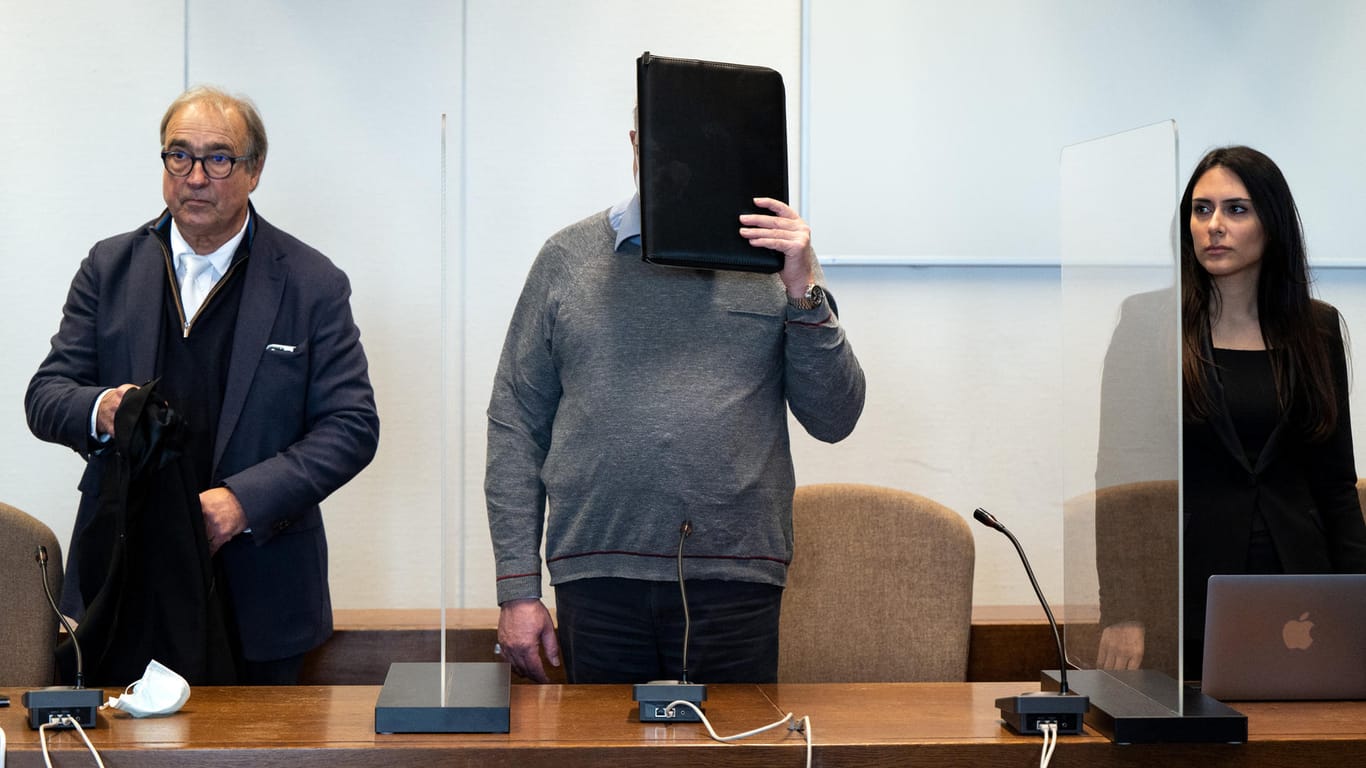 Der katholische Priester (Mitte) hält sich im Gerichtssaal eine Mappe vor das Gesicht: Die Anklage wirft ihm unter anderem schweren sexuellen Kindesmissbrauch vor.