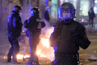 Polizisten stehen an der Eisenbahnstraße vor Einkaufwagen mit brennenden Gegenständen. Im Leipziger Osten ist es in der Neujahrsnacht zu Ausschreitungen gekommen.