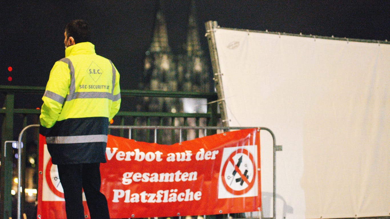 Ein Mitarbeiter eines Sicherheitsdienstes steht vor einer Böllerverbotszone am Rhein: Die Silvesternacht in Köln verlief weitgehend störungsfrei.