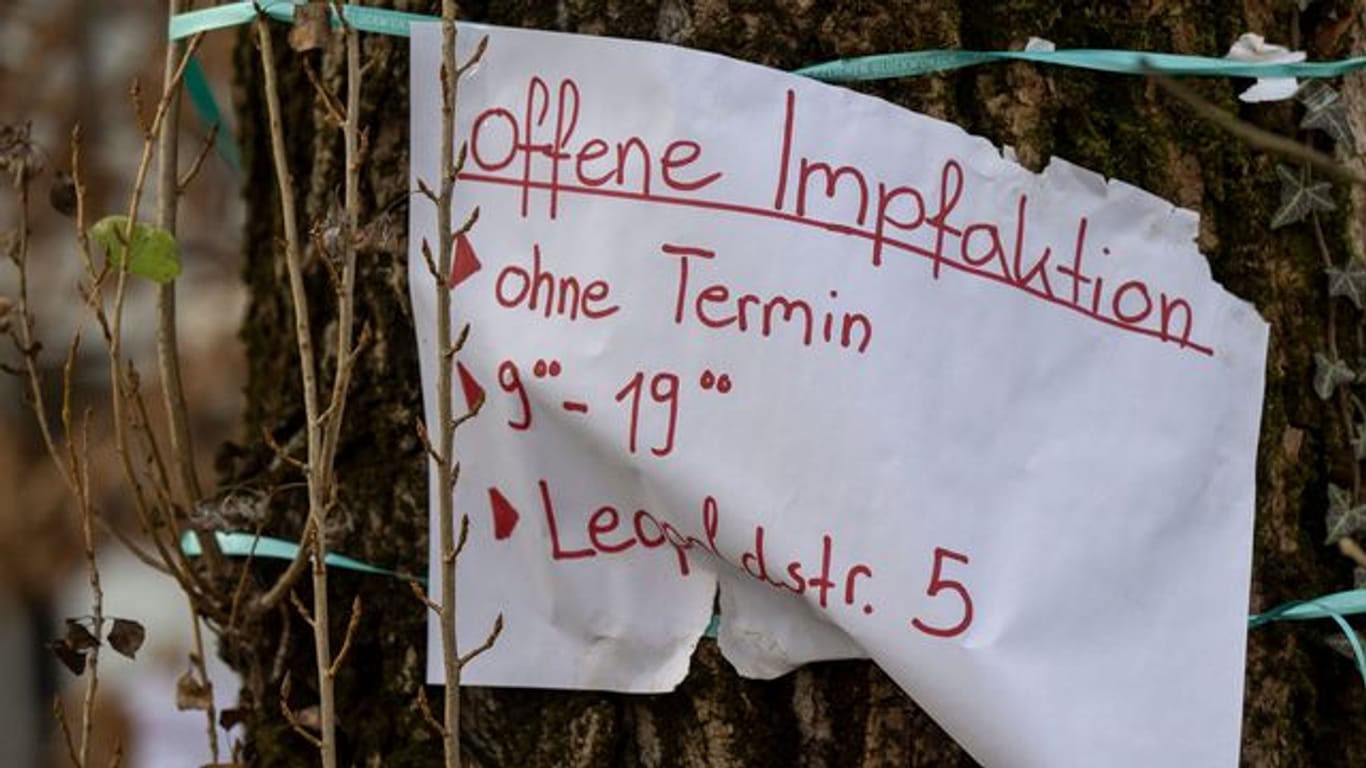 Ein Zettel mit der Aufschrift "offene Impfaktion" hängt an einem Baum in München-Schwabing.