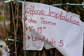 Ein Zettel mit der Aufschrift "offene Impfaktion" hängt an einem Baum in München-Schwabing.