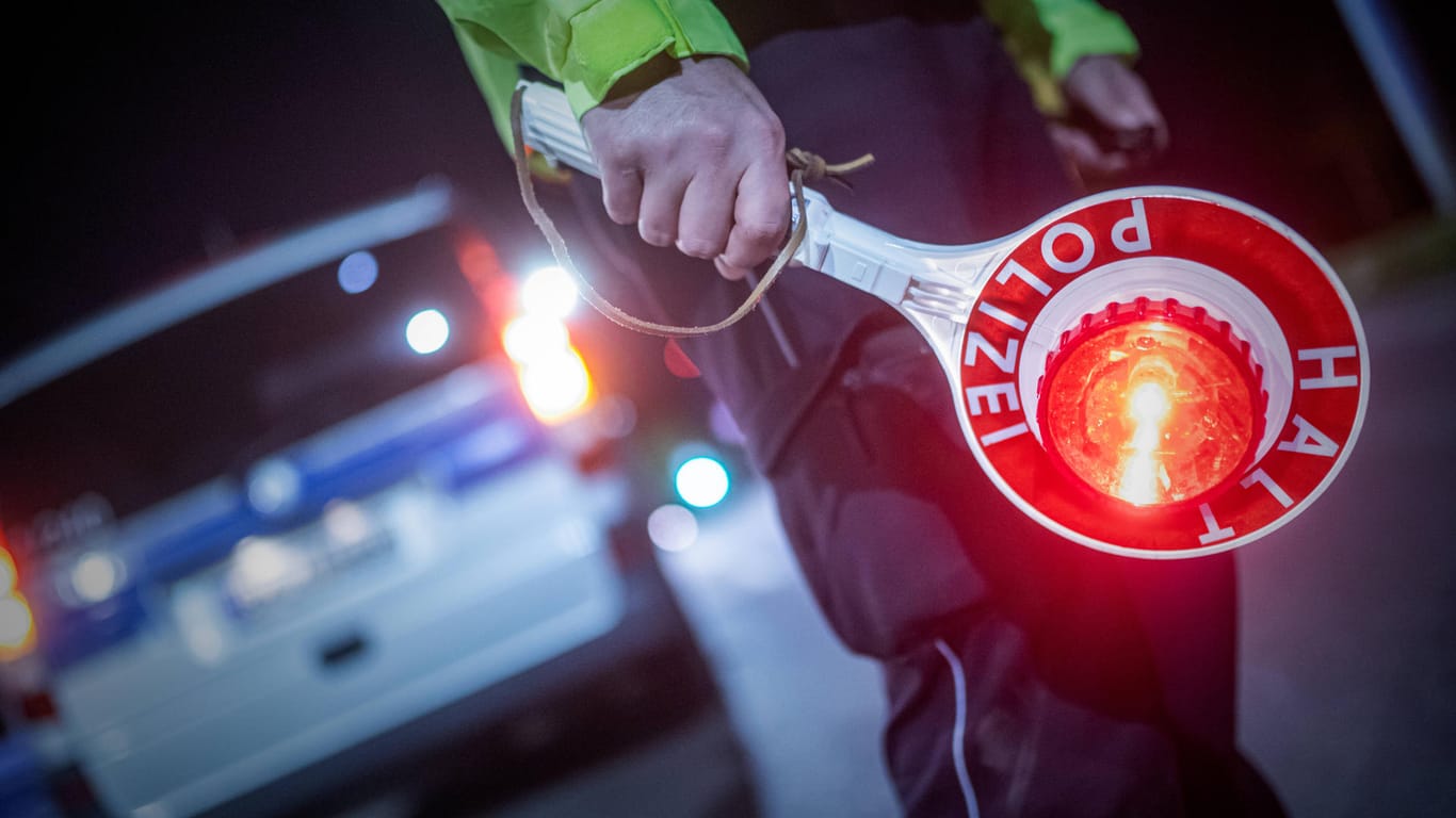 Ein Polizist hält eine Kelle mit dem Schriftzug "Stopp" in der Hand (Symbolbild): Eine mögliche Tatwaffe wurde bei einem alkoholisierten Autofahrer entdeckt.