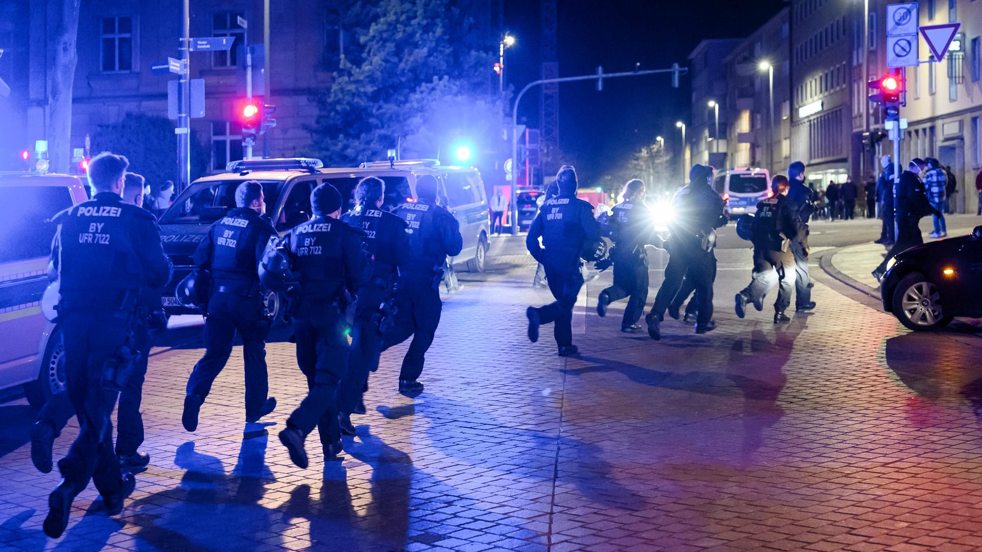 Eine Einheit der Polizei bereitet sich auf die Räumung eines Platzes in Schweinfurt vor und läuft über die Straße.