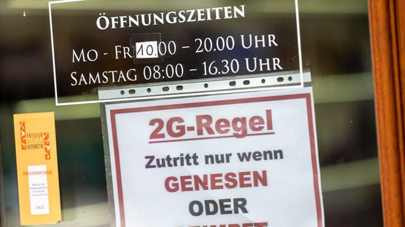 Ein Schild zur "2G-Regel" hängt an der Eingangstür eines Münchner Friseurladens.