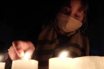 Eine Frau entzündet Kerzen im Gedenken an Opfer der Pandemie: In Neuenbürg hat das Virus vier Kinder zu Waisen gemacht. (Symbolfoto)