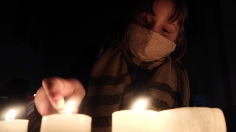 Eine Frau entzündet Kerzen im Gedenken an Opfer der Pandemie: In Neuenbürg hat das Virus vier Kinder zu Waisen gemacht. (Symbolfoto)