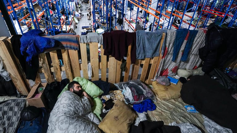 Ein Mann schläft in einem Logistikzentrum an der belarussisch-polnischen Grenze: Auch im neuen Jahr harren weiter hunderte Migranten an der Grenze aus.