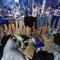 Ein Mann schläft in einem Logistikzentrum an der belarussisch-polnischen Grenze: Auch im neuen Jahr harren weiter hunderte Migranten an der Grenze aus.