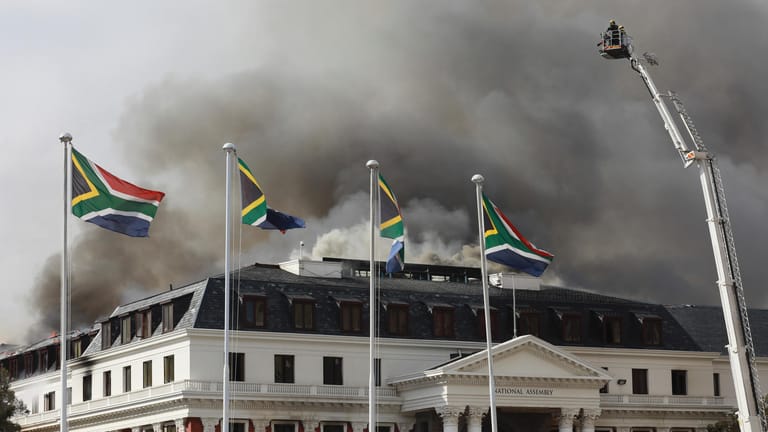 Rauch steigt aus dem Parlament auf, nachdem das Feuer am späten Nachmittag wieder aufflammte: Ein Großbrand im Parlamentsgebäude von Südafrika in Kapstadt zerstörte am Neujahrswochenende den Sitzungssaal vollständig und brachte teile des Dachs zum einstürzen.