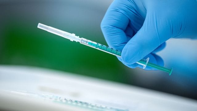Ein medizinischer Mitarbeiter hält eine Impfspritze in der Hand Ein medizinischer Mitarbeiter hält eine Impfspritze in der Hand