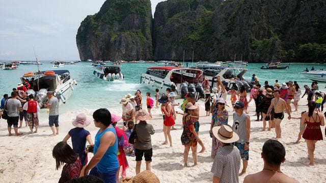 Touristen besuchen den Strand Maya Bay.