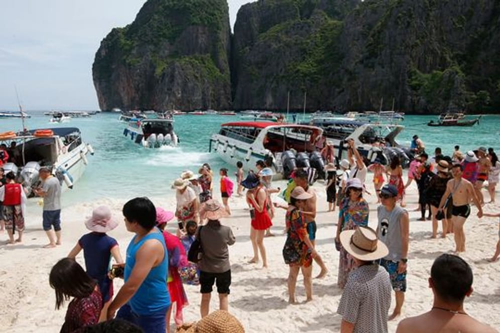 Touristen besuchen den Strand Maya Bay.
