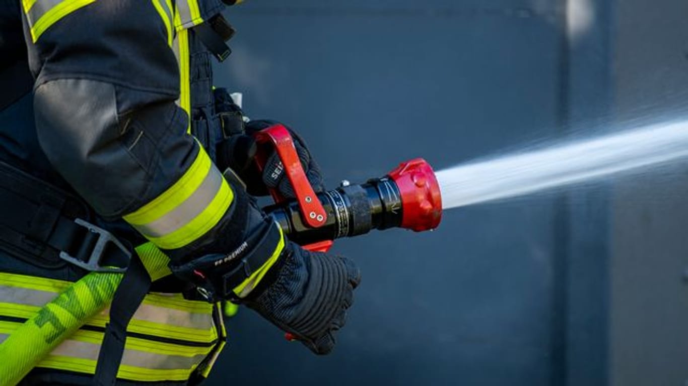 Ein Mitglied der Feuerwehr spritzt aus einem Schlauch mit Wasser (Symbolbild): Eine Tiefgarage ist in Flammen aufgegangen.