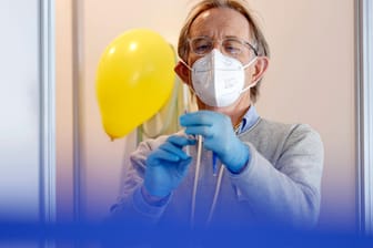Vor einer Impfkabine mit Luftballons für Kinder posiert ein Impfarzt mit einer Spritze (Archivbild): Noch sind nicht genügend Menschen in Deutschland mehrfach geimpft.