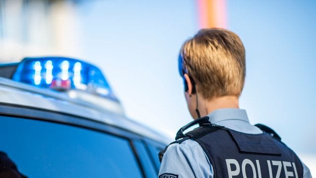 Eine Polizistin steht vor einem Streifenwagen