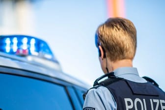 Eine Polizistin steht vor einem Streifenwagen