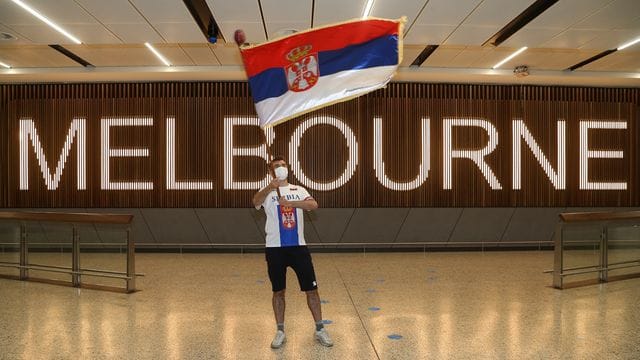 Ein Fan von Novak Djokovic schwenkt in der Ankunftshalle des Flughafens Melbourne eine serbische Fahne. Ein Fan von Novak Djokovic schwenkt in der Ankunftshalle des Flughafens Melbourne eine serbische Fahne.
