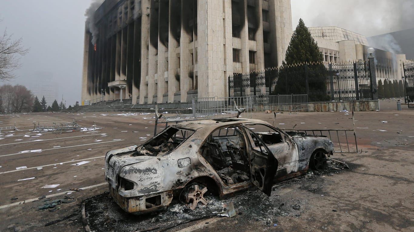 Almaty: Nach Krawallen steht ein ausgebranntes Fahrzeug vor dem Regierungssitz der Millionenmetropole.