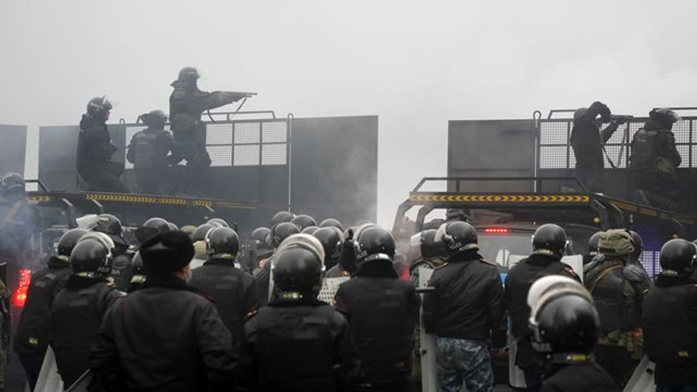 Schwerbewaffnete Bereitschaftspolizisten blockieren in Almaty eine Straße, um Demonstranten aufzuhalten.