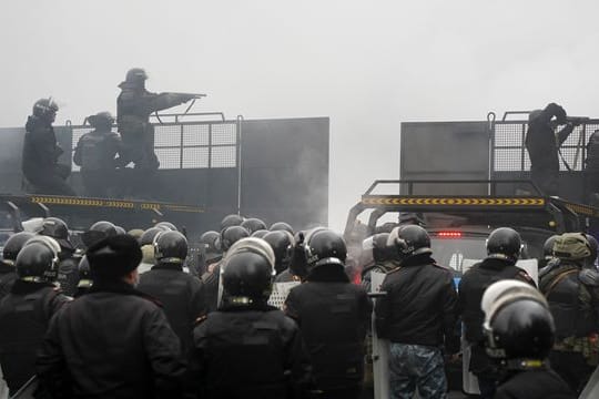 Schwerbewaffnete Bereitschaftspolizisten blockieren in Almaty eine Straße, um Demonstranten aufzuhalten.