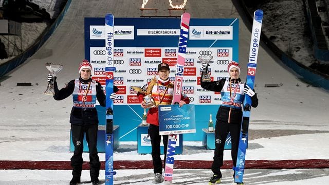 Ryoyu Kobayashi (M) jubelt mit dem Pokal für den Gesamtsieger, einem goldenen Adler, neben dem Gesamtzweiten Marius Lindvik (l) und dem Gesamtdritten Halvor Egner Granerud.