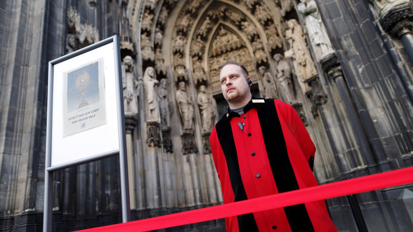 Ein Domschweizer vor dem Eingang des Kölner Doms (Symbolbild): Klimaaktivisten haben einen Gottesdienst im Kölner Dom unterbrochen.