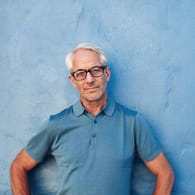 Älterer Mann vor einer blauen Wand