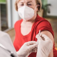 Ein Arzt hält eine Impfspritze (Symbolbild): Britische Daten zeigen, dass Booster Senioren wirksam schützen.