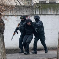 Bewaffnete Bereitschaftspolizisten halten einen Demonstranten in Almaty fest: Die Unruhen in dem zentralasiatischen Land Kasachstan halten an.