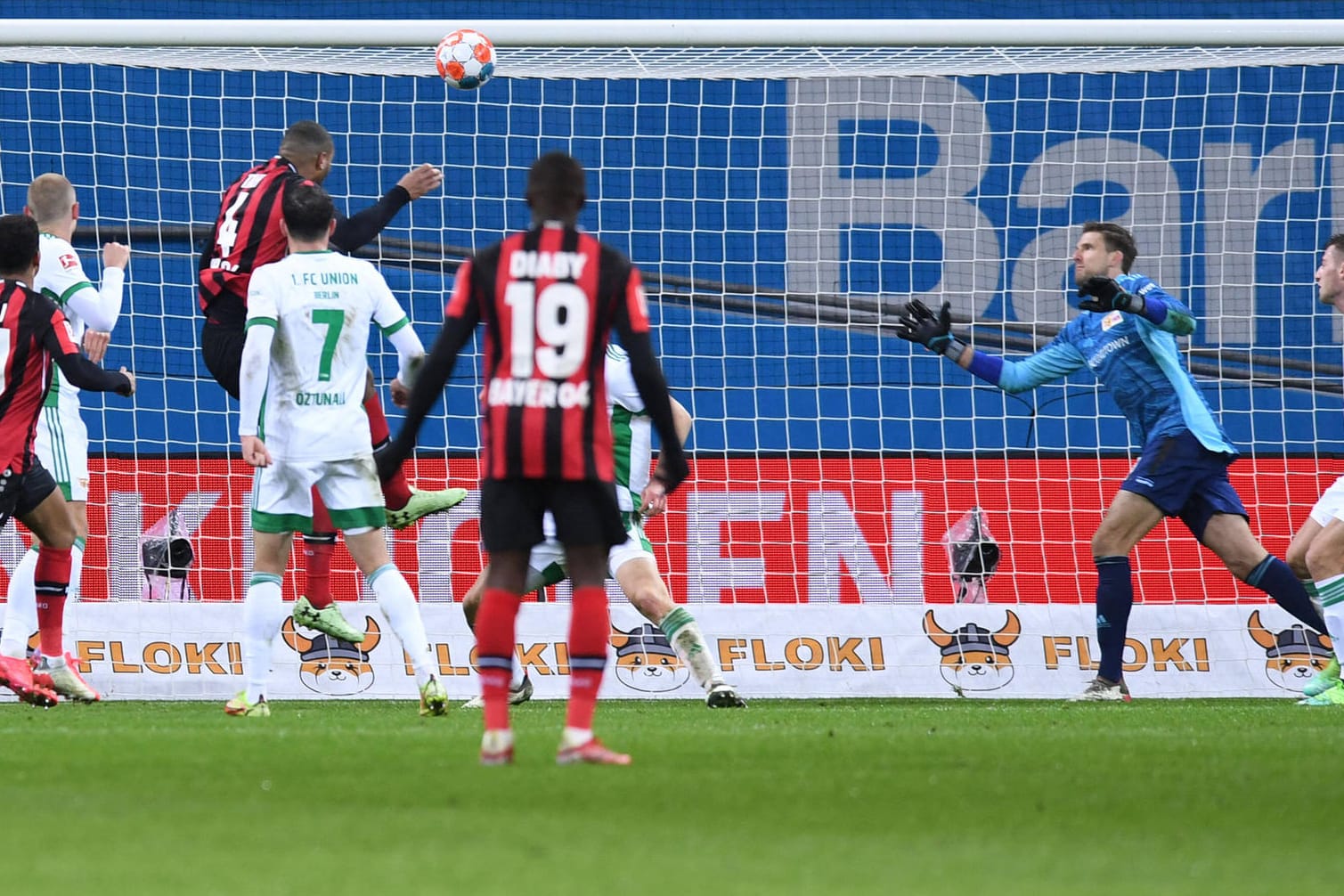 Leverkusens Tah schraubt sich hoch und köpft, Union-Keeper Luthe (r.) ist ohne Chance.