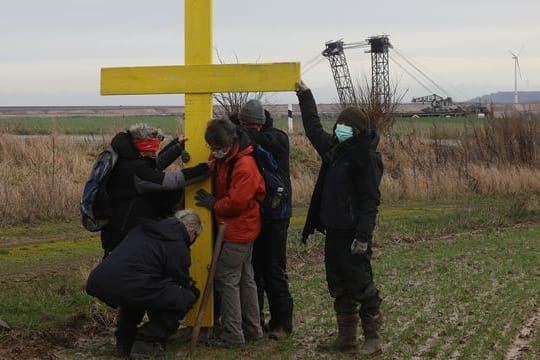 Demonstranten stellen am Rande des Braunkohletagebaus bei Lützerath ein gelbes Kreuz auf.