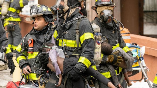 Feuerwehrleute tragen Kinder aus einem Wohnhaus in der Bronx.