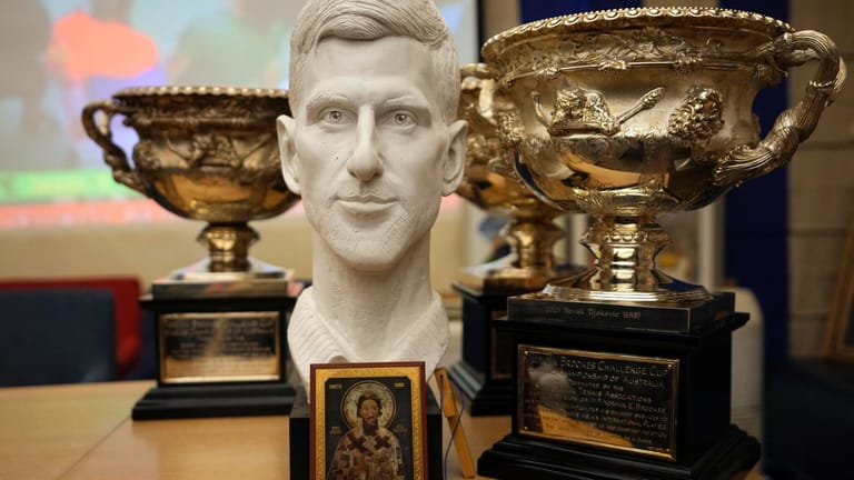 Pokale und ein religiöses Bildnis sind während einer Pressekonferenz um die Büste des serbischen Tennisspielers Novak Djokovic aufgestellt.