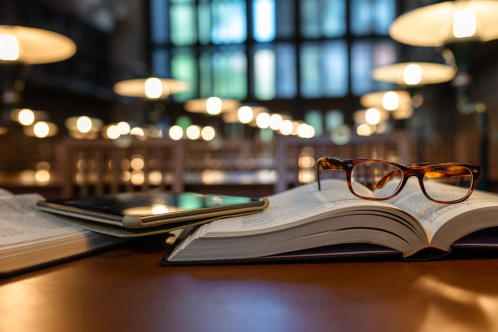 Ein Tablet und eine Brille liegen in der Bibliothek