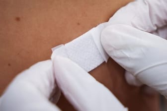 Eine Ärztin klebt einem Mann nach der Impfung ein Pflaster auf den Arm (Symbolbild): Wer mit dem abgelaufenen Impfstoff geboostert wurde, bekommt jetzt eine Viertimpfung angeboten.