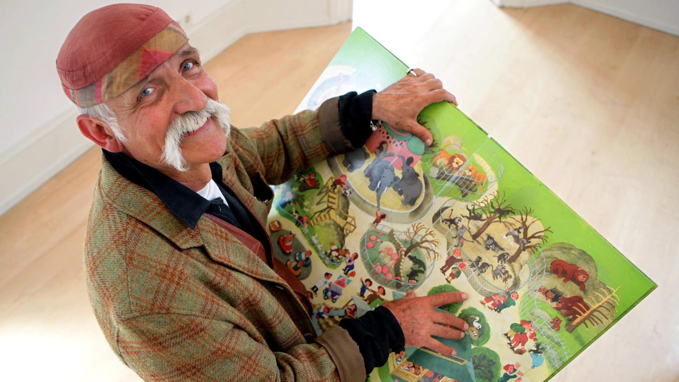 Ali Mitgutsch: Der Grafiker hält eines seiner Kinderbücher in Händen.