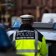 Ein Polizeibeamter steht zwischen zwei Einsatzfahrzeugen: In Weimar ist ein Mann mit einer Pistole bedroht worden.