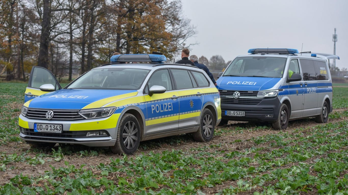 Zwei Einsatzwägen auf einem Feld (Archivbild): Ein 33-Jähriger hat sich in Sachsen eine Verfolgungsjagd mit der Polizei geliefert.